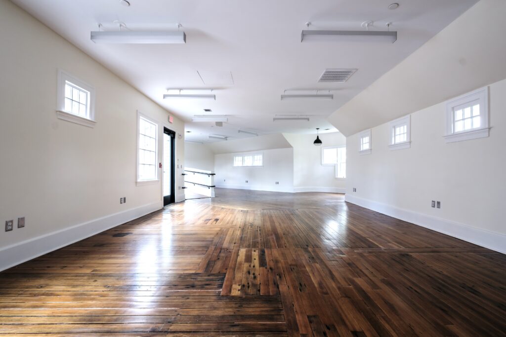 A photo inside the historic events venue The Annex including the front door on a bright day with the natural light shining on the dark wooden floors.