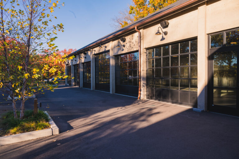 The exterior of Garage B, showcasing the large glass overhead doors and the outdoor patio space.