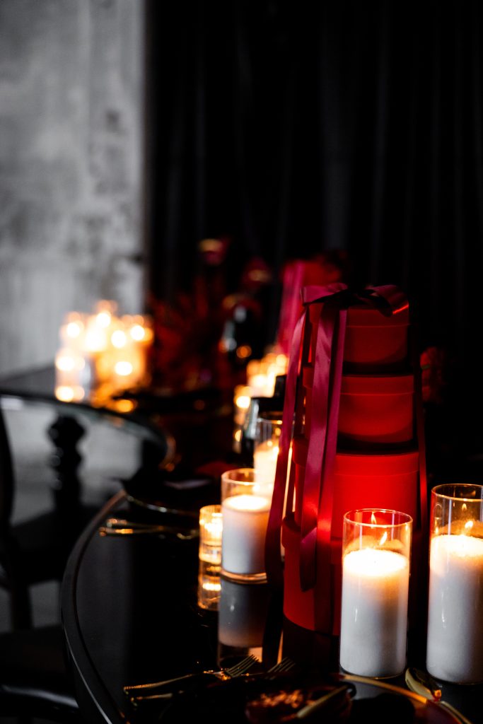A serpentine tablescape with stacked gift box decorations and arrangements of pillar candles.