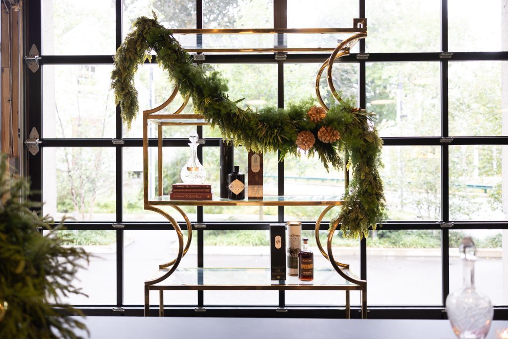 Gilded bar shelving decorated with a fir garland set against a window.