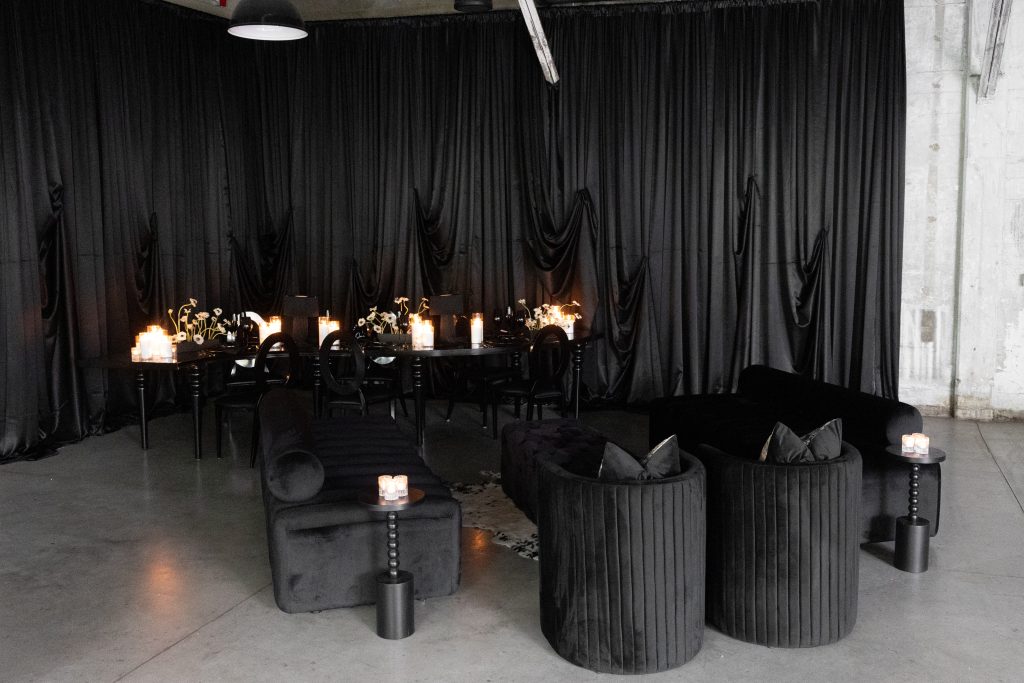 All-black dining and lounge areas staged against a black designed drapery backdrop.