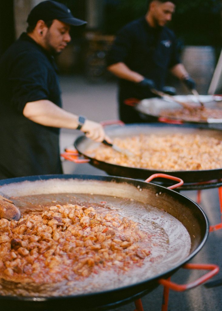 Two cooks tend to three large paella pans.