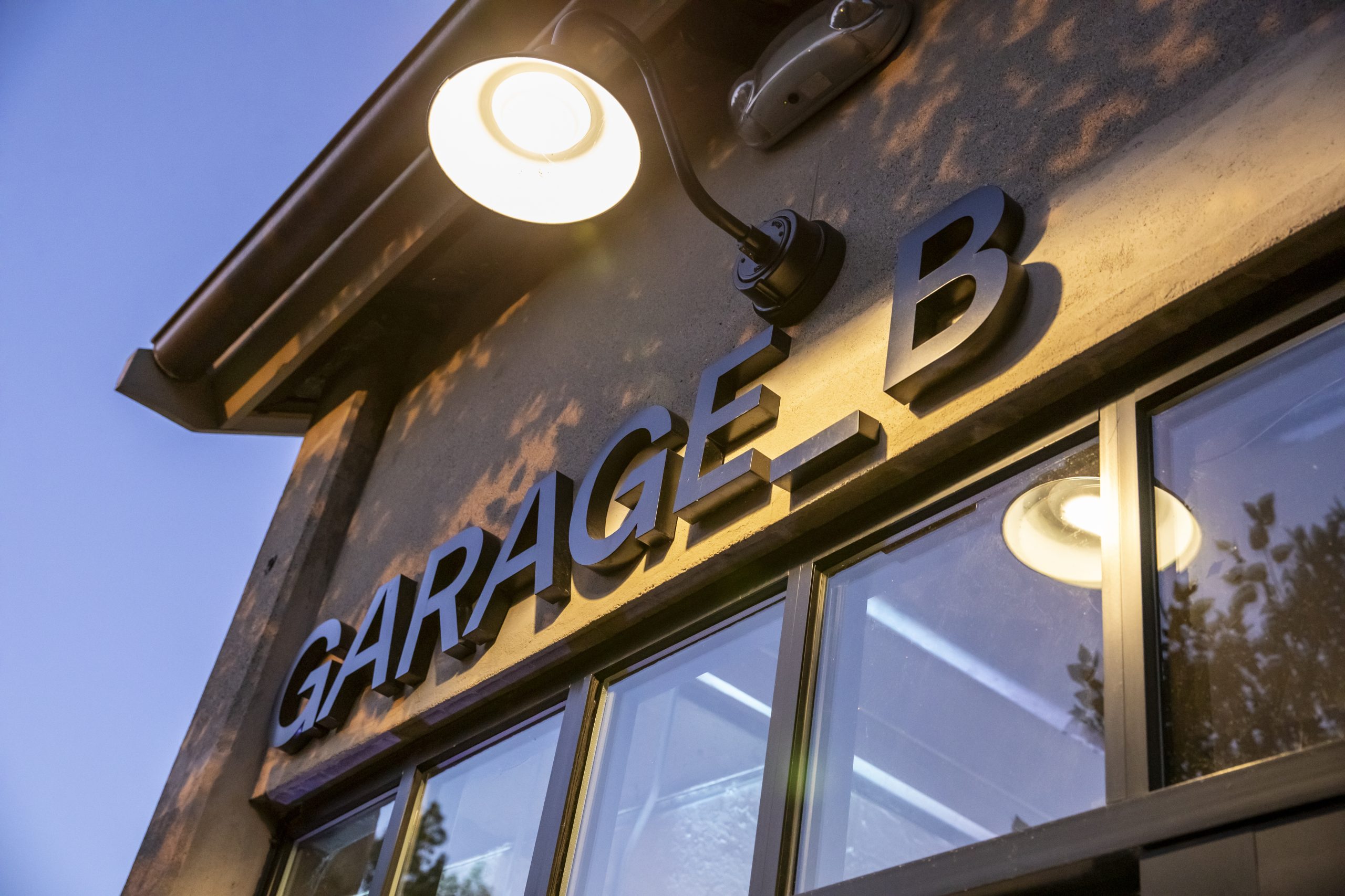 Garage B's exterior signage lit underneath an outdoor sconce.