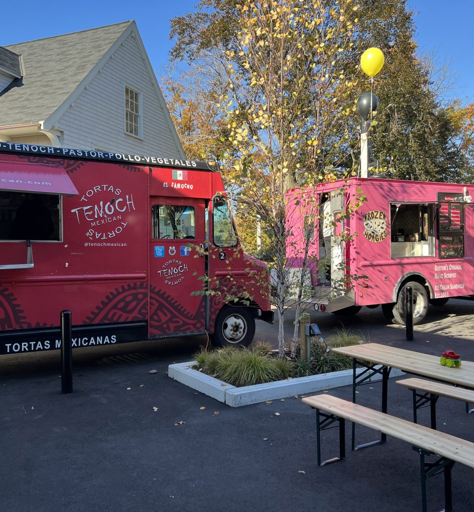 Two food trucks parked at a patio.