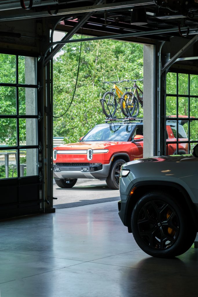 Two SUVs parked both inside and outside of a venue with operable floor-to-ceiling garage-style overhead doors.