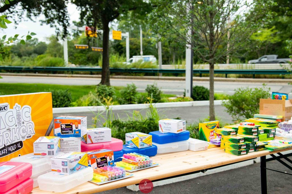 A collection of school supplies on a table at a patio with Soldiers Field Road in the background.