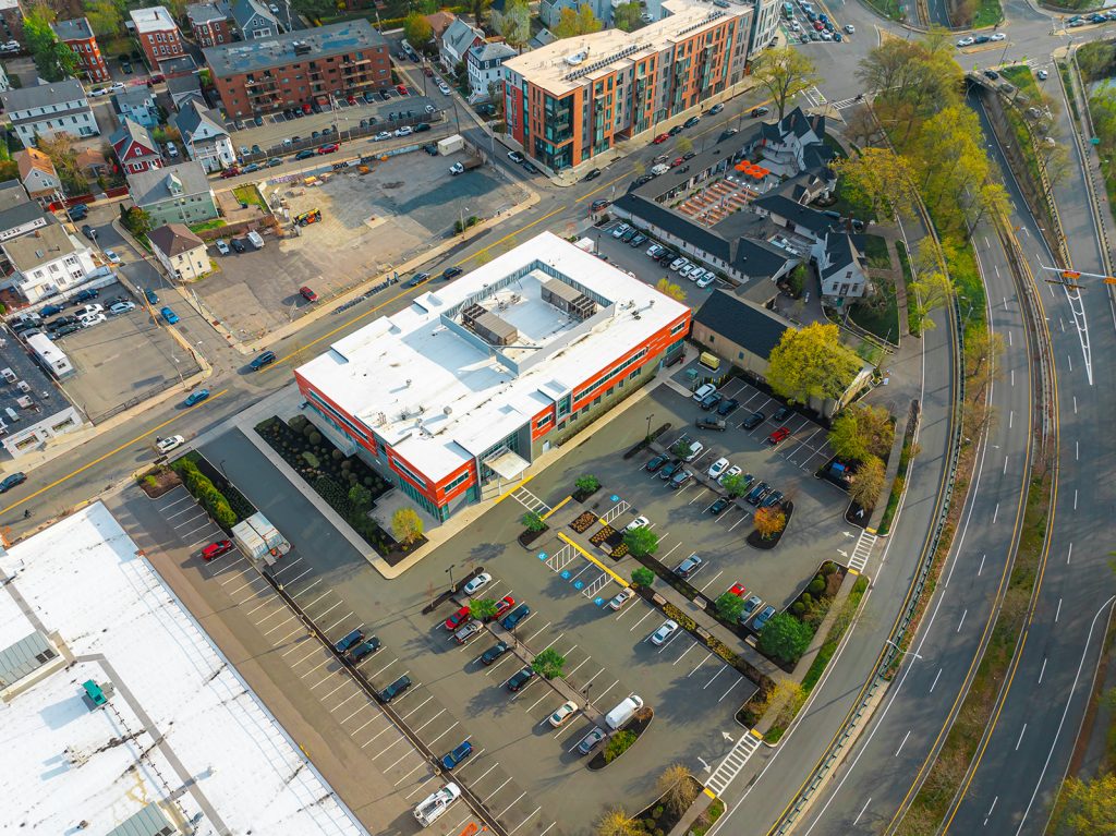 An aerial view of the Charles River Community Health center and its parking lot and the next-door Charles River Speedway site.