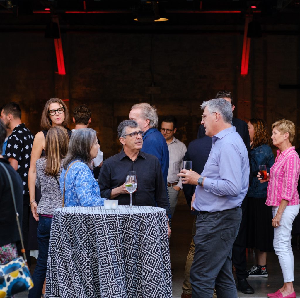 People mingle with drinks at a high-top table