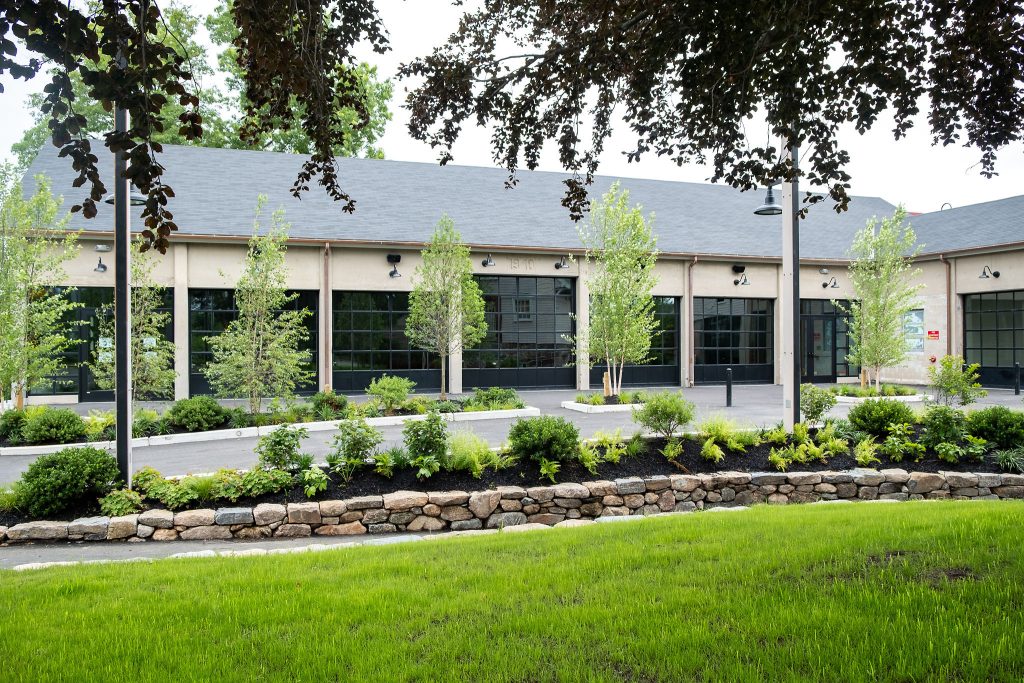 An exterior view of Garage B that features the bank of glass overhead doors and the adjacent outdoor patio and driveway.