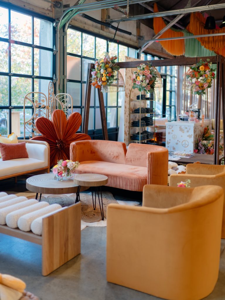 A lounge area comprised of sofas and accent chairs in warm tones agains a bank of floor-to-ceiling windows.