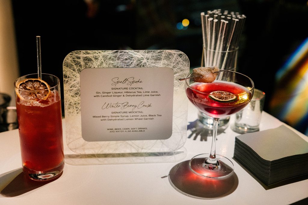 A display of two cocktails and a placard describing them as a "Spell Spoke" and a "Winter Berry Crush".